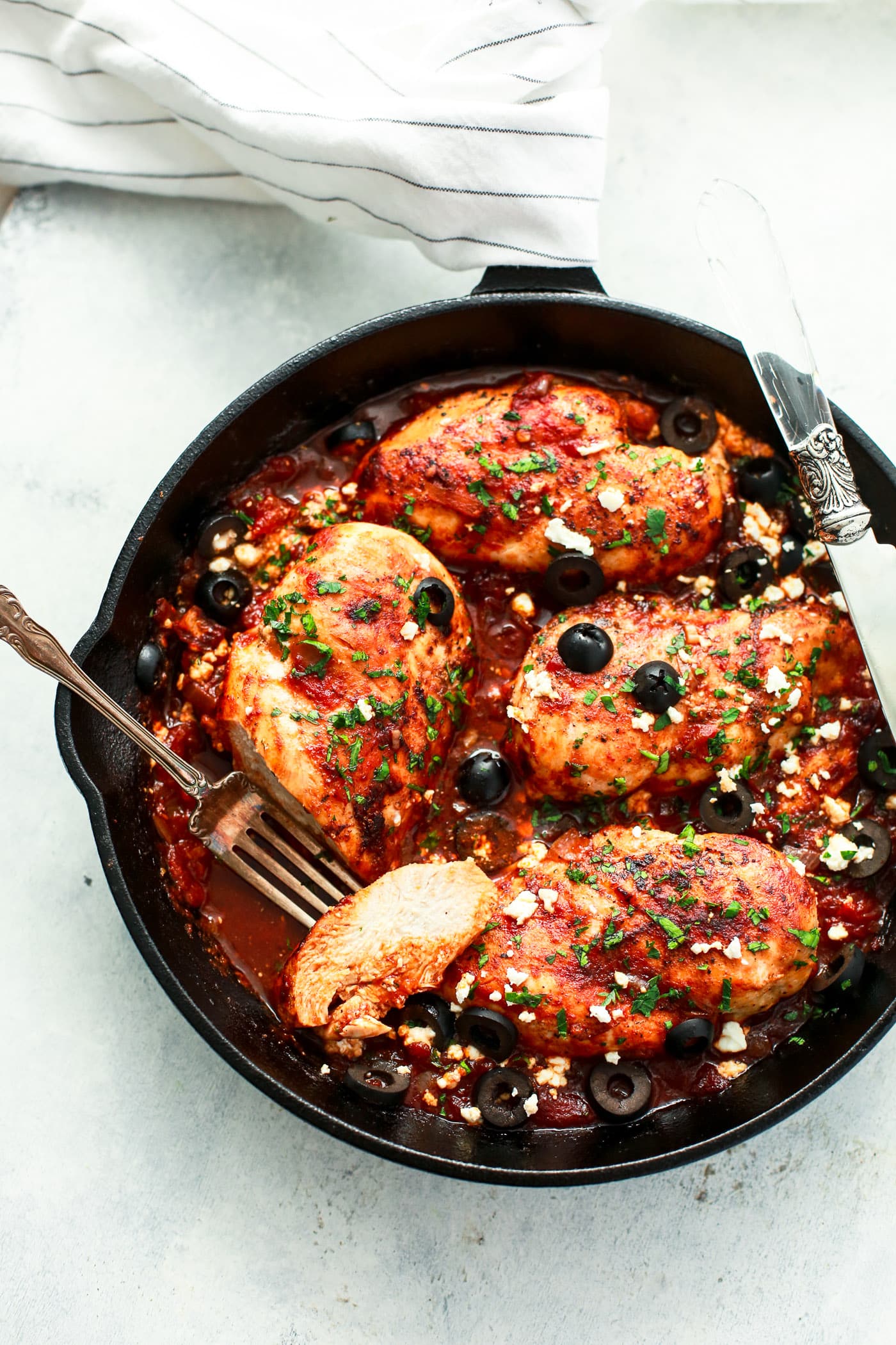 overhead view of a white skillet containing Mediterranean Chicken breast