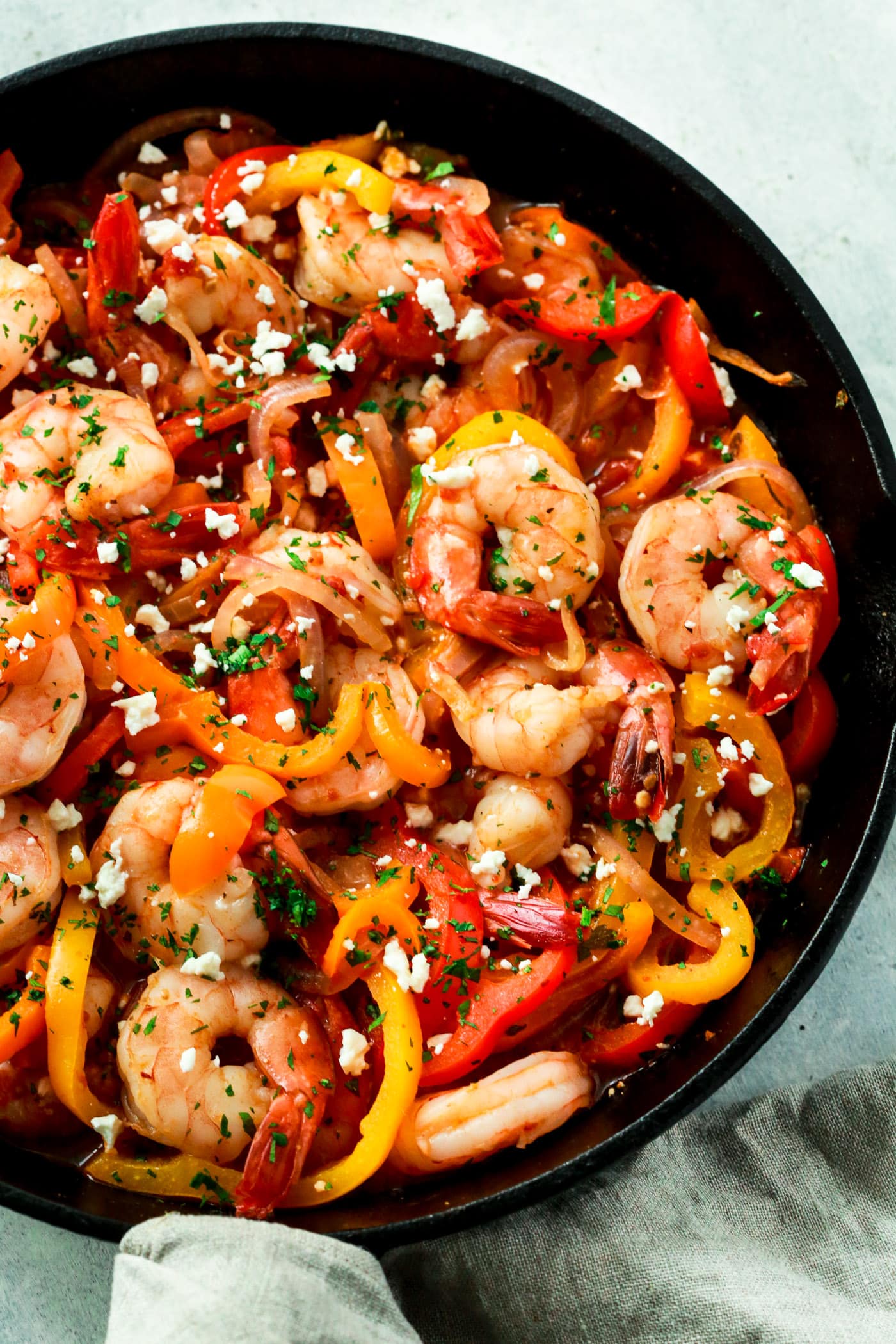 close up of a cast iron with shrimp, bell pepper, and onions. 