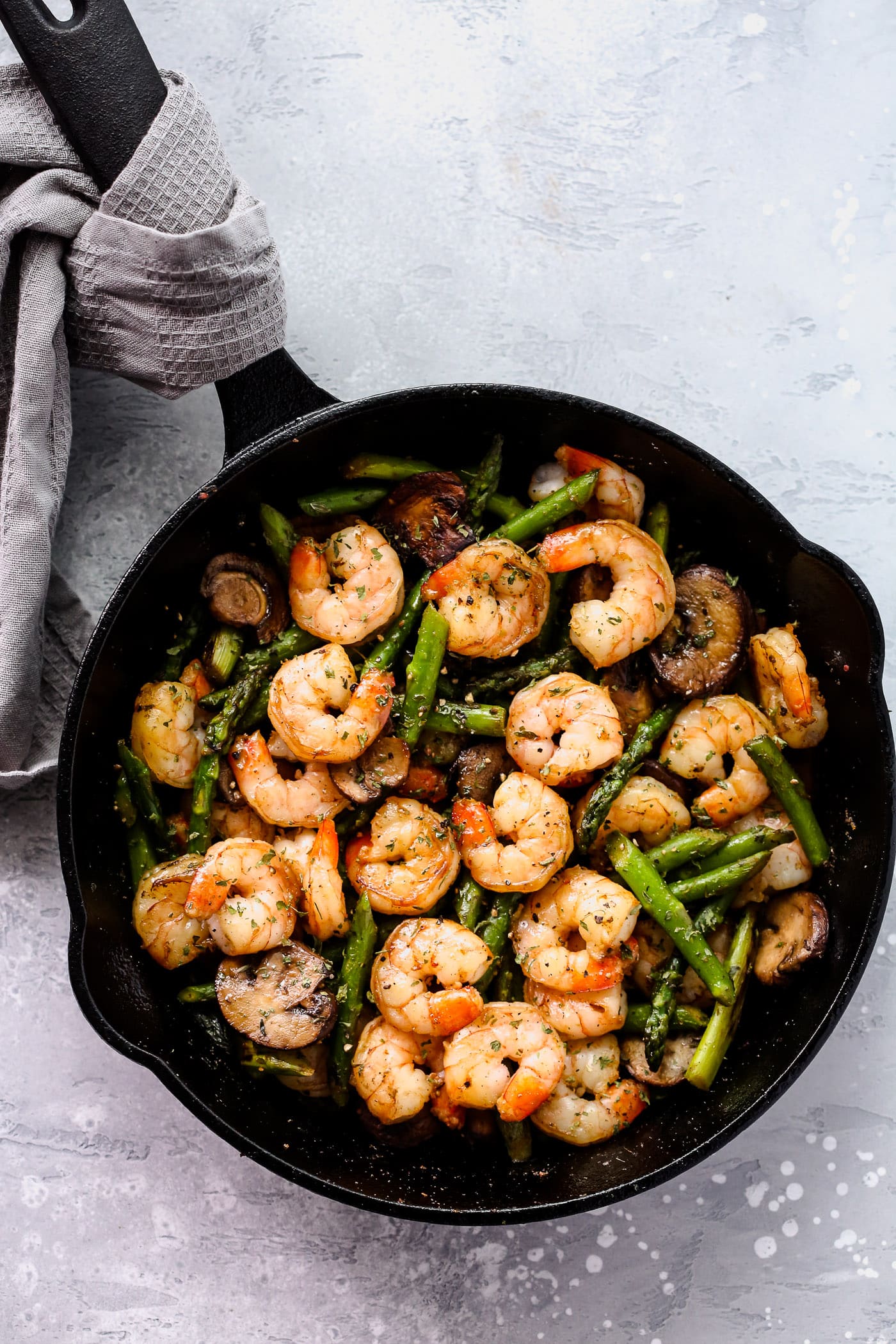 One-Pan Dinner Recipe - A cast iron with garlic shrimp, asparagus, and mushrooms.