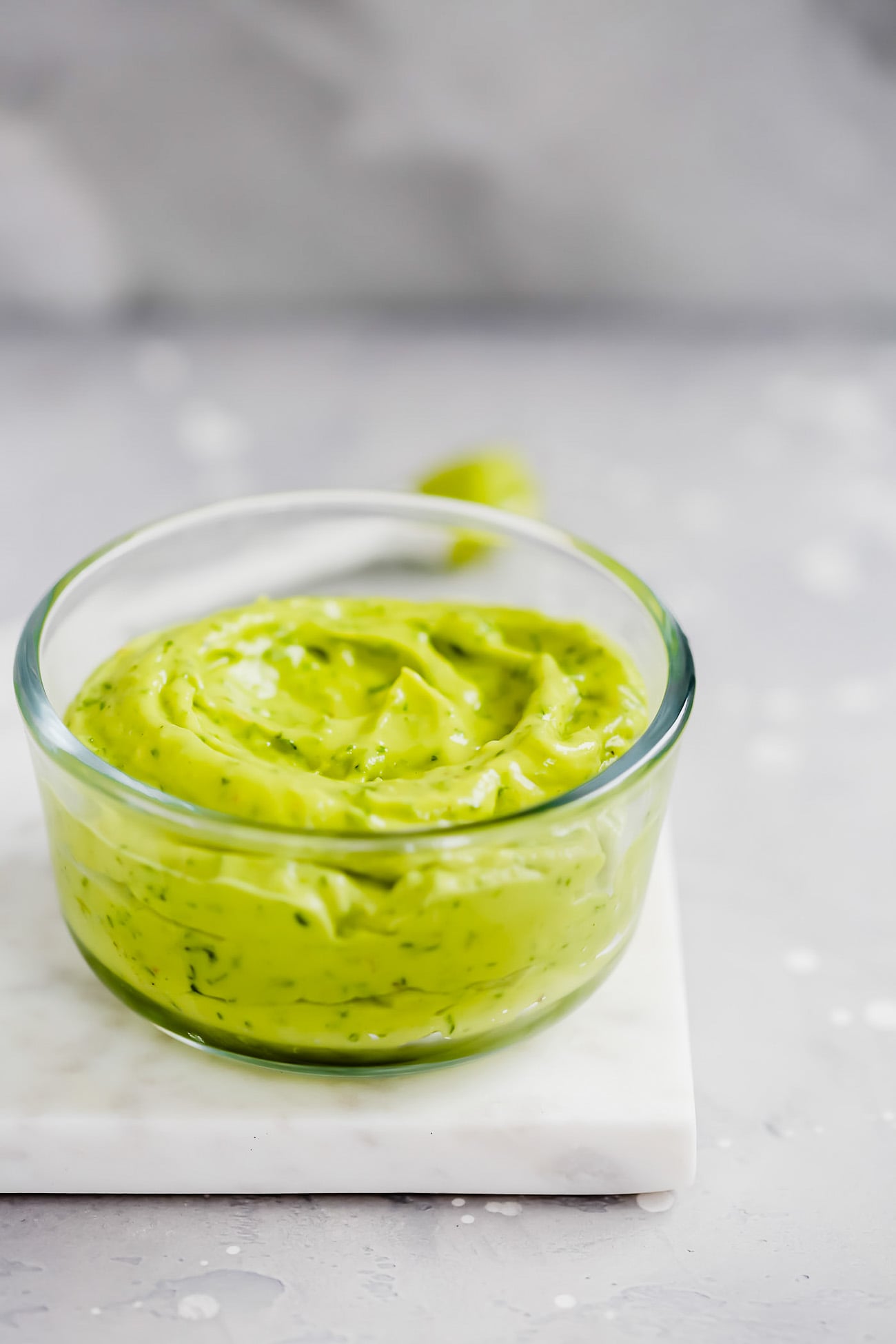 Close-up of Creamy Avocado Sauce in a glass bowl on a marble board.