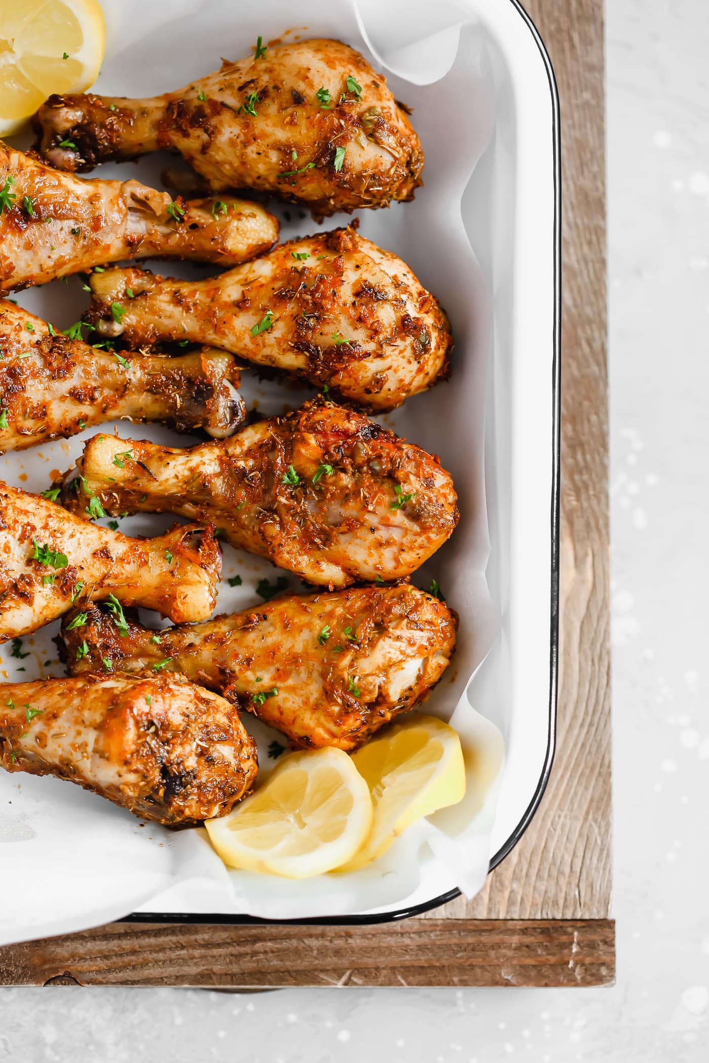 Roasted chicken legs on a baking sheet garnished with lemon.