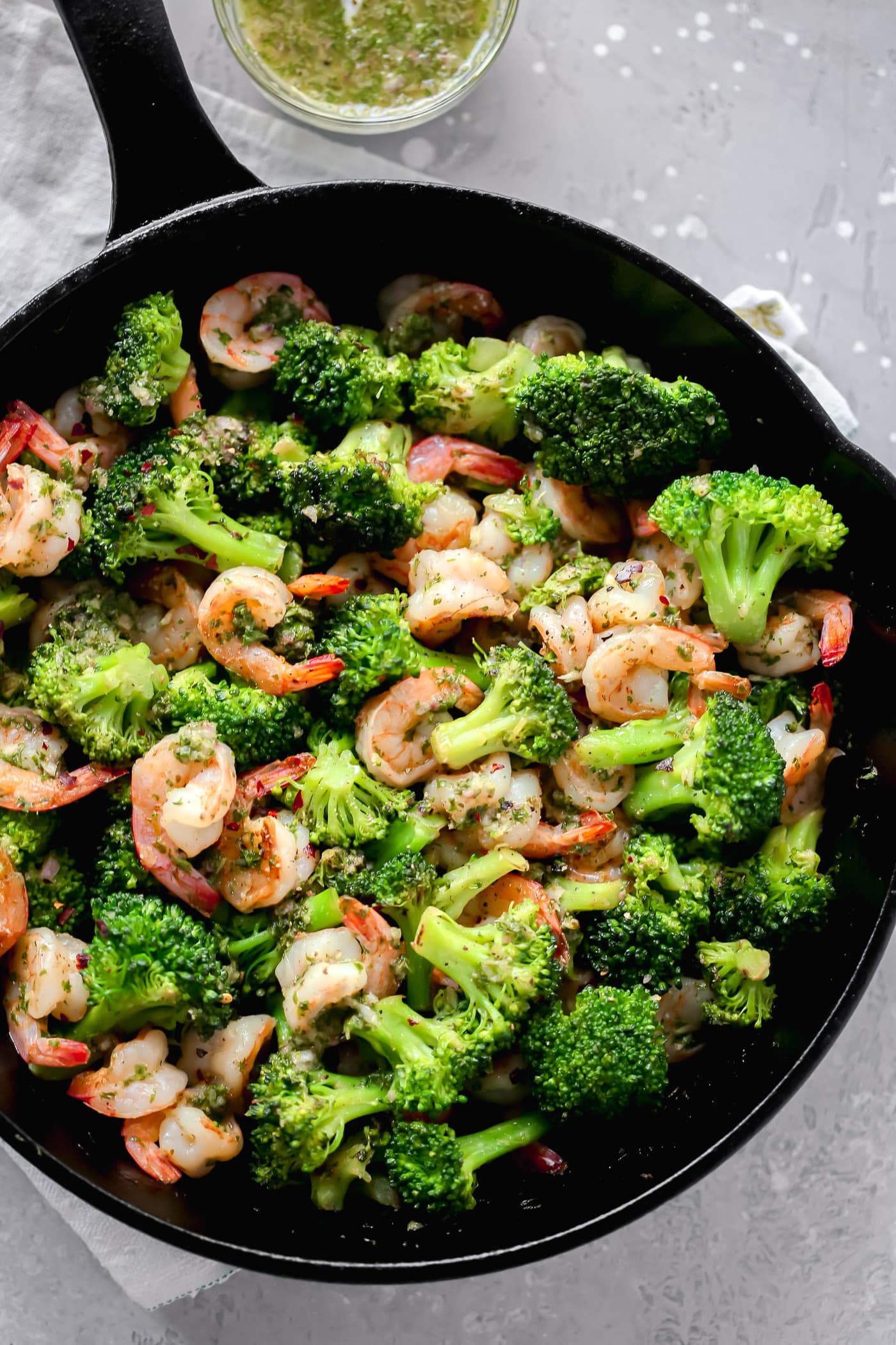 overhead view of a cast iron skillet containing shrimp and broccoli