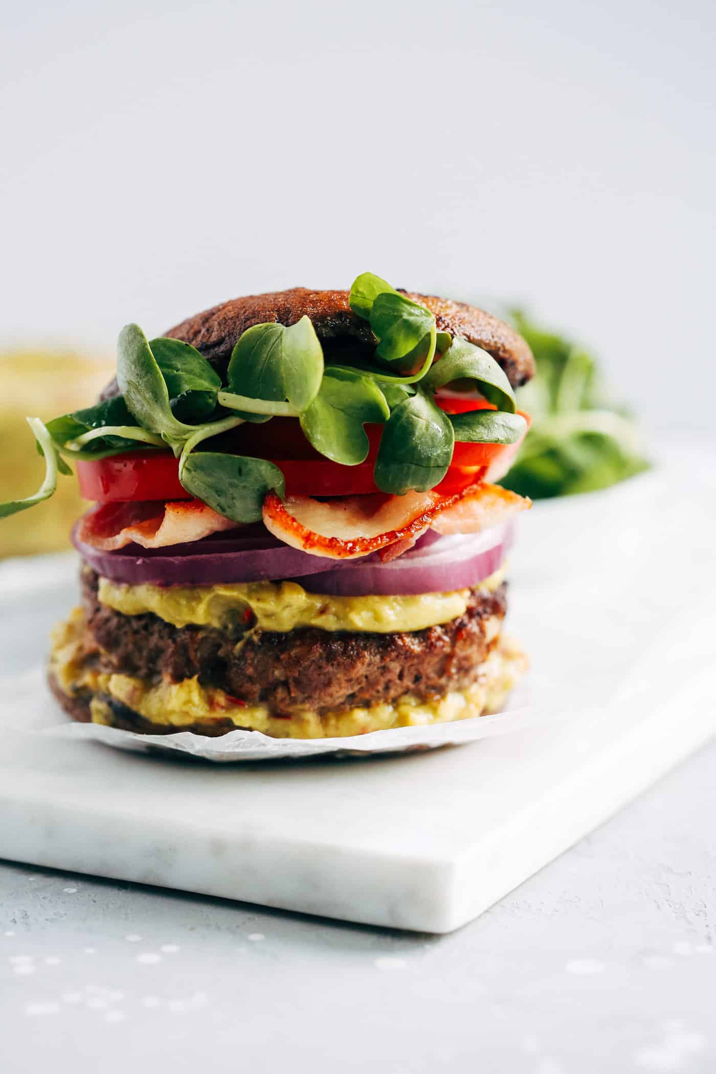 close-up of burger with guacamole on a white marble