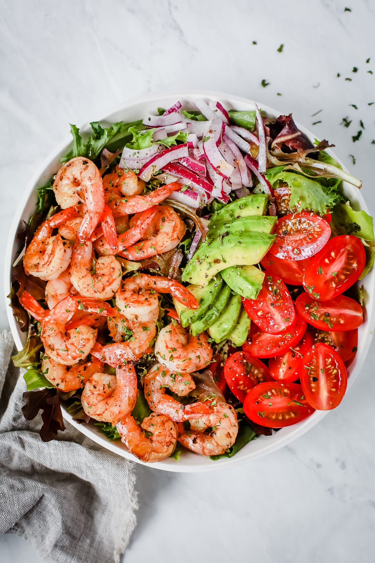 shrimp and tomato salad in a white bowl on a marble board
