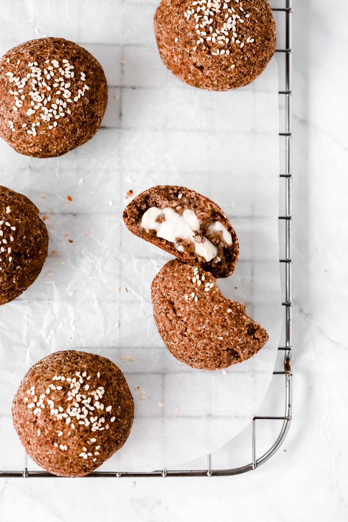 Overhead photo of a dinner roll cut opened on a cooling rack.