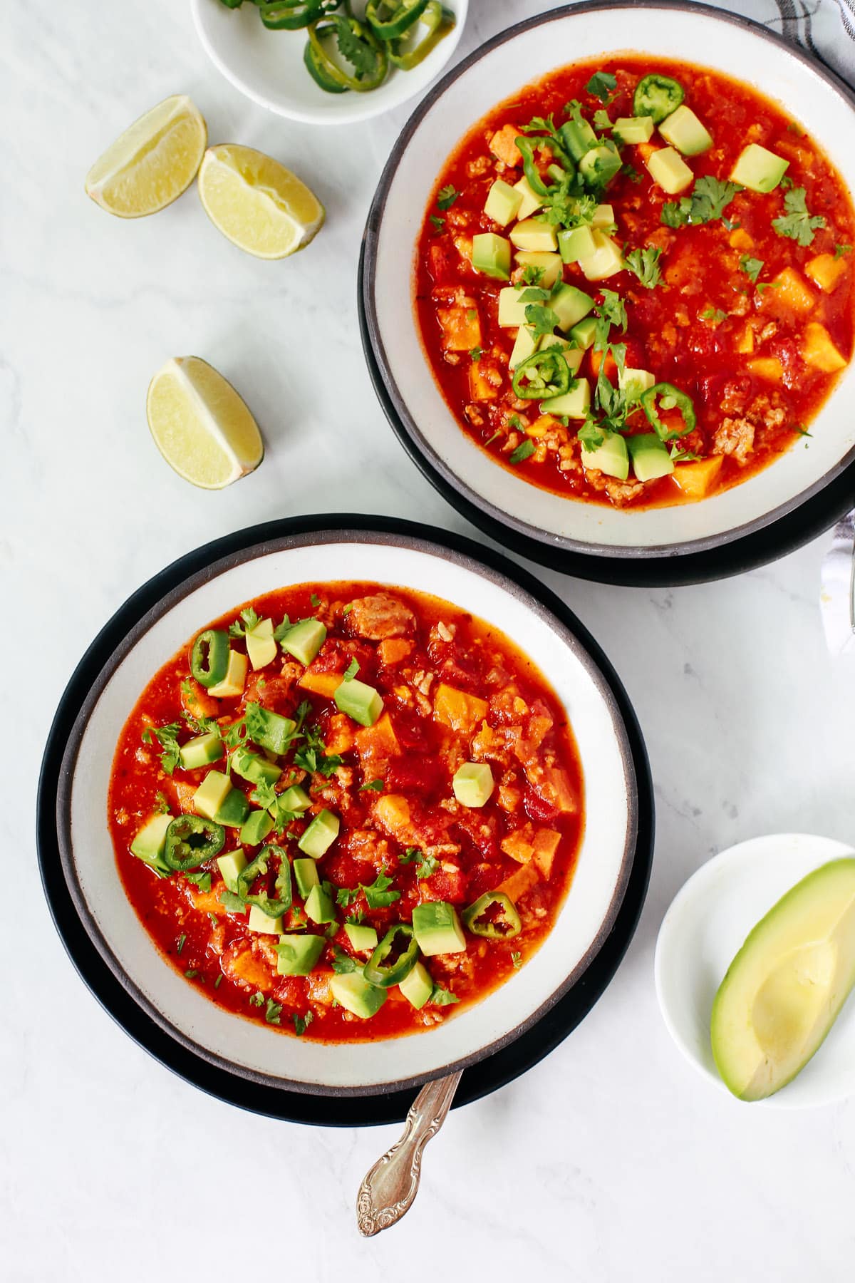 overhead view of two black rimmed bowls of pumpkin chili. 