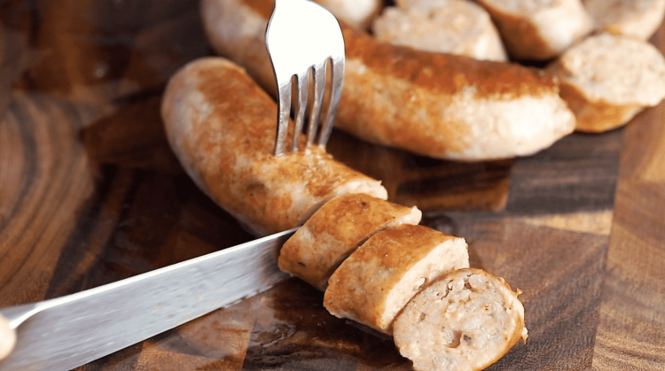 cutting sausage in a wooden cutting board