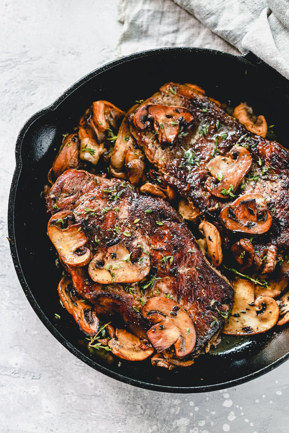 overhead view of a white skillet containing steak with mushroom