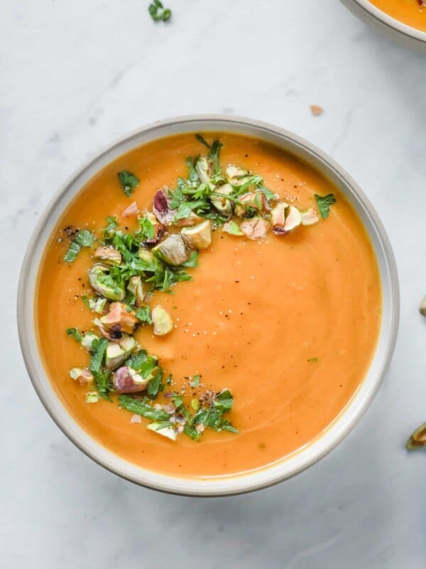 Overhead photo of a white bowl with butternut squash soup with garnish.