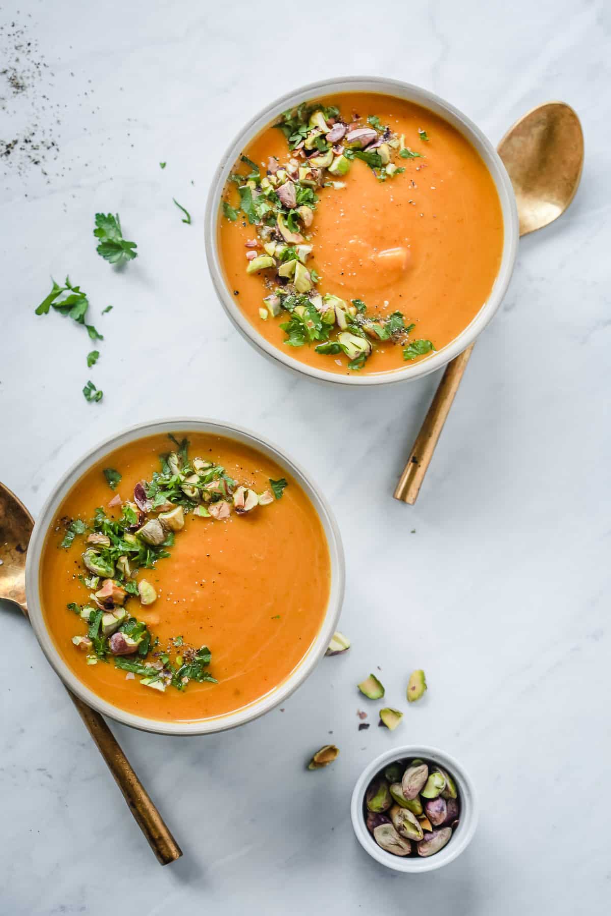 Two bowls of butternut squash soup with garnish on top.