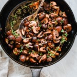 Overhead photo of a cast iron pan with garlic butter mushrooms inside.