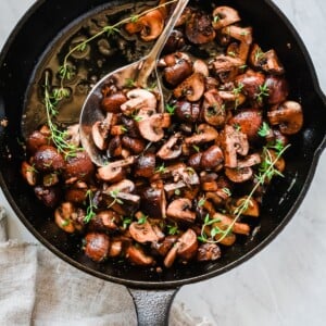 Overhead photo of a cast iron pan with garlic butter mushrooms inside.