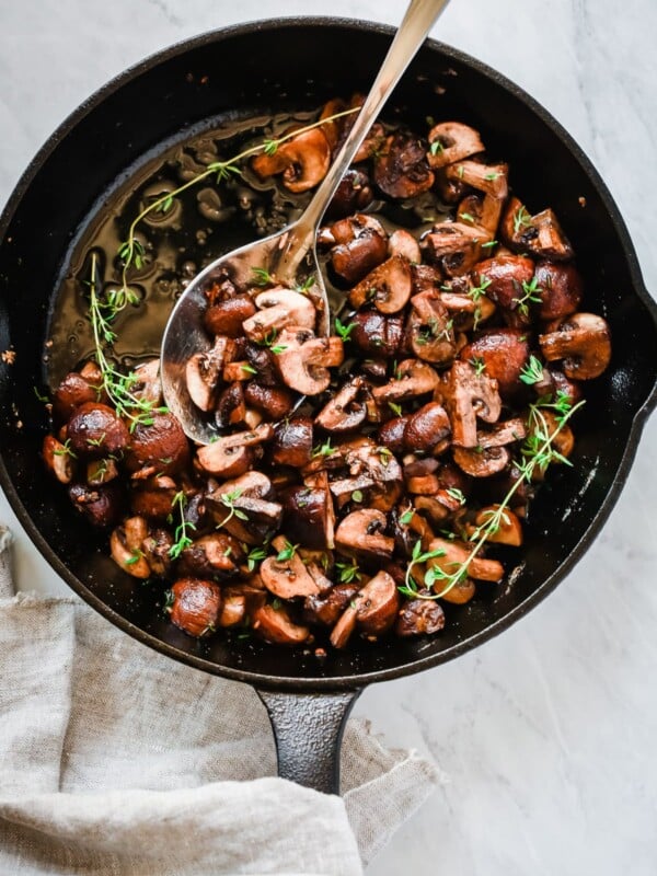 Overhead photo of a cast iron pan with garlic butter mushrooms inside.