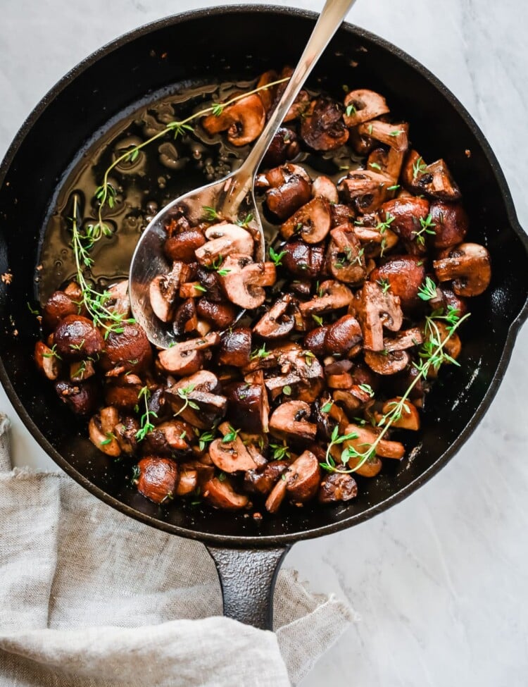 Overhead photo of a cast iron pan with garlic butter mushrooms inside.