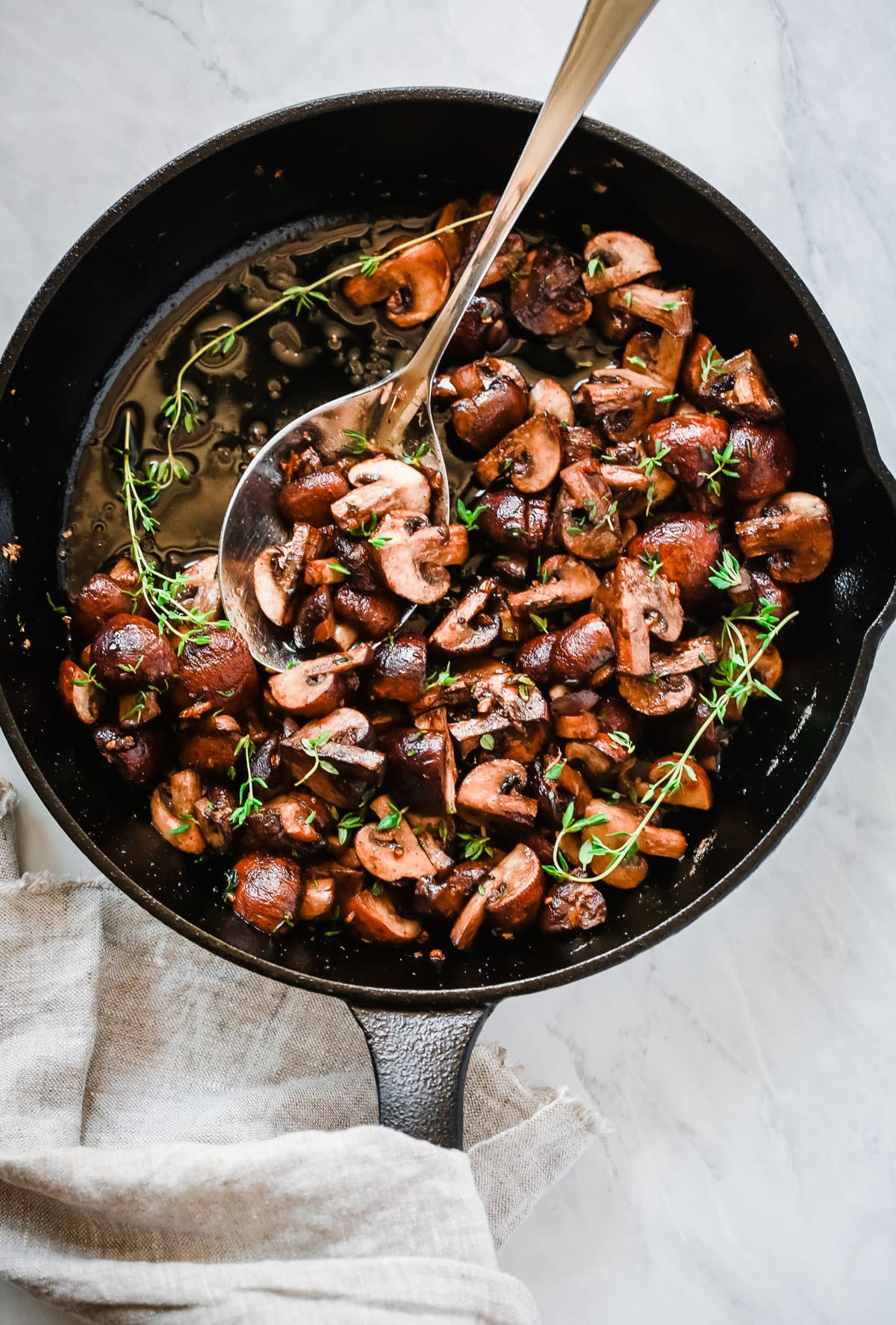 Overhead photo of a cast iron pan with garlic butter mushrooms inside.