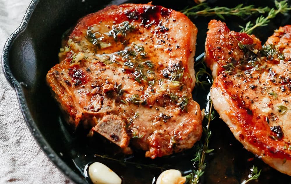 closeup photo of pork chops in a cast iron skillet