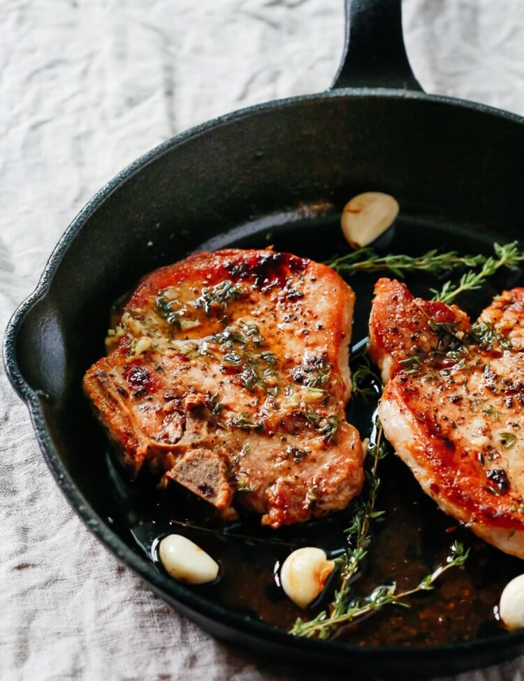 overhead view of Garlic Butter Baked Pork Chops in a cast iron skillet