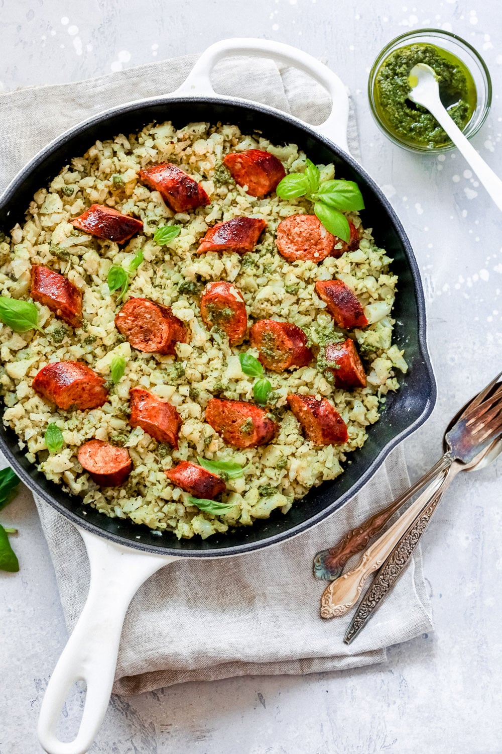 White skillet with Italian sausage and cauliflower rice.