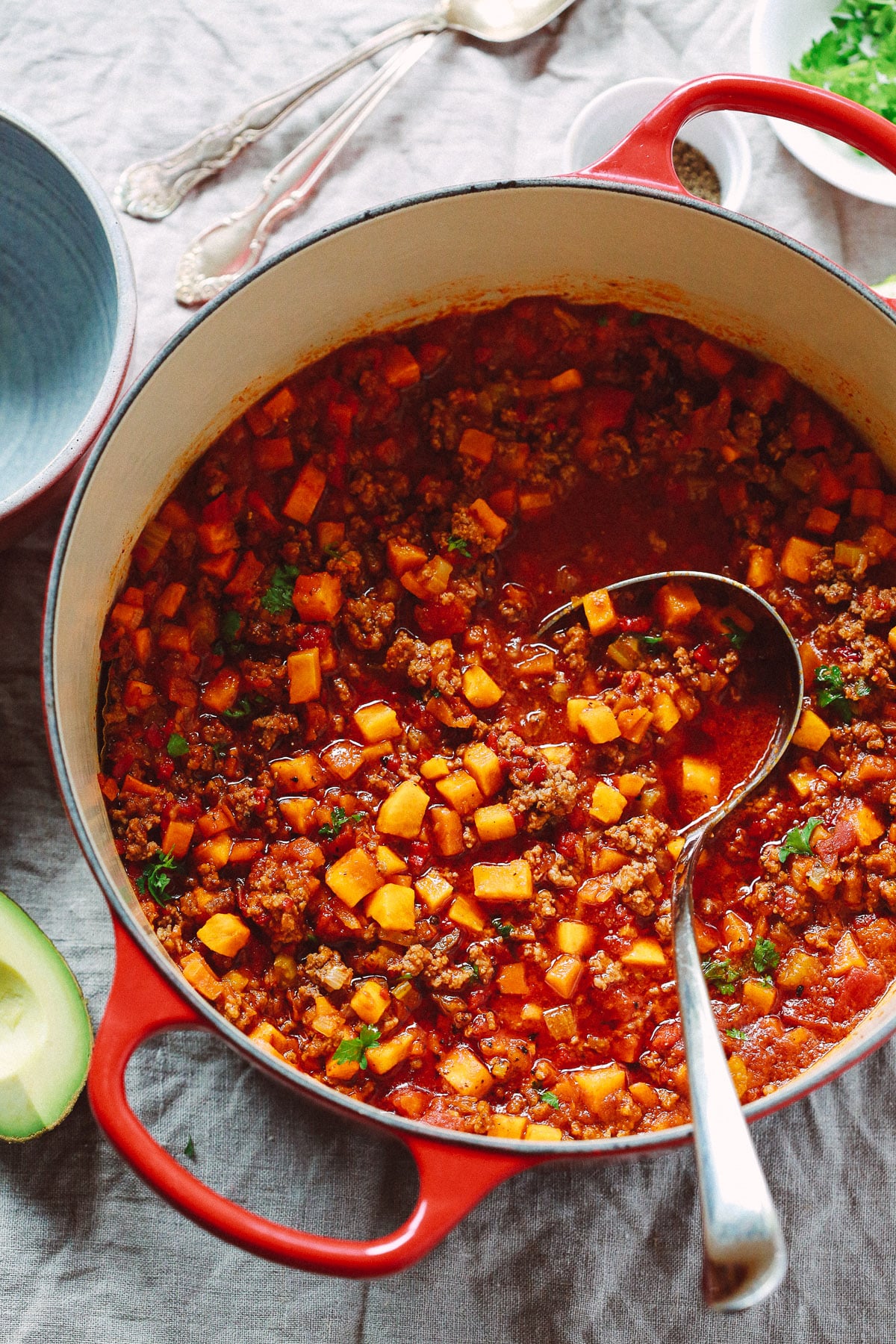 Overhead view of butternut squash chili in a Dutch oven with a ladle inside.