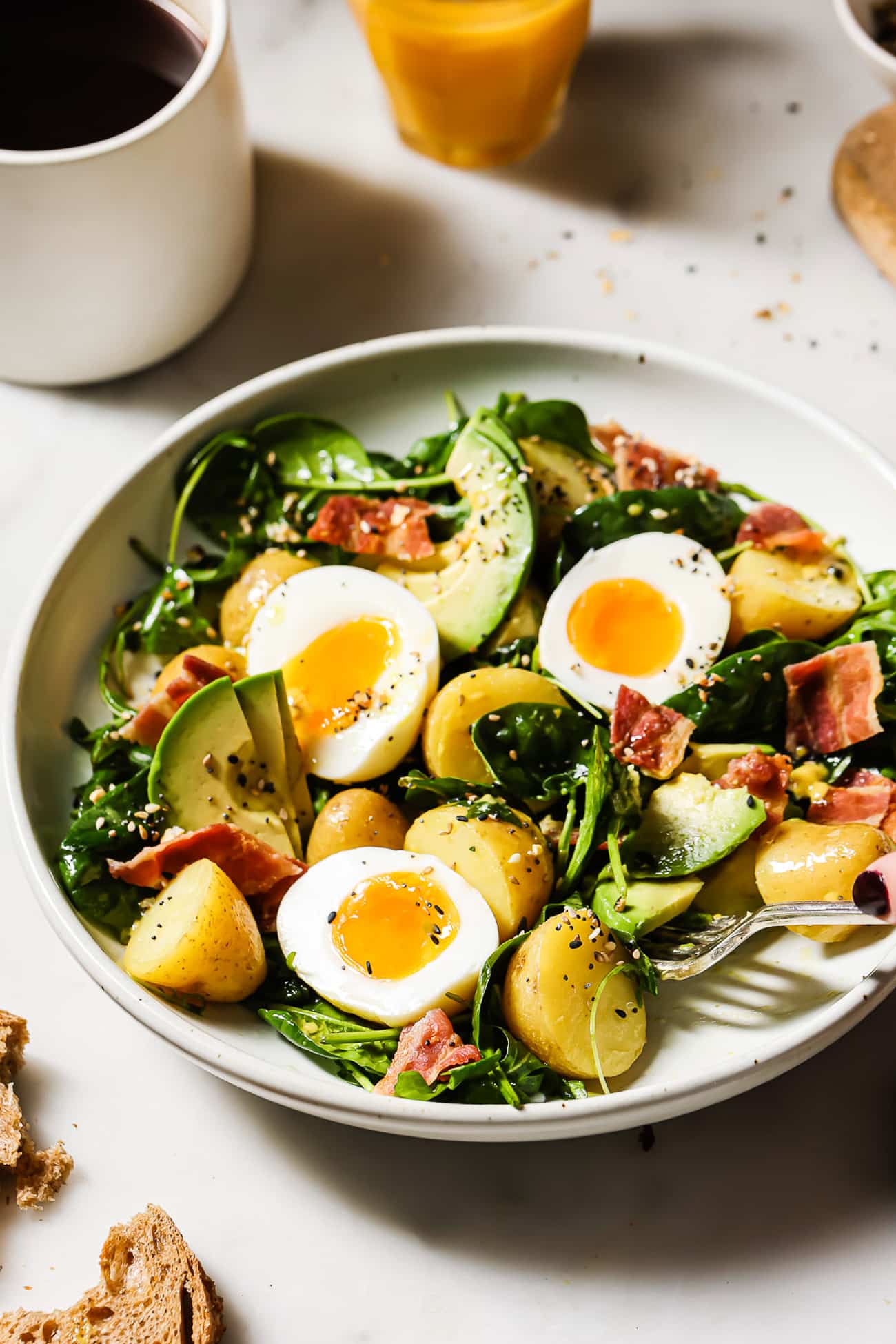 An overhead view of a breakfast salad with bacon, eggs, and avocado.