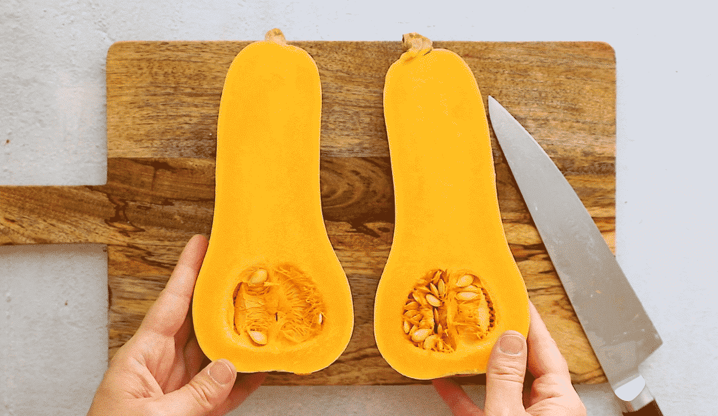 butternut squash cut in half lengthwise on a wooden cutting board