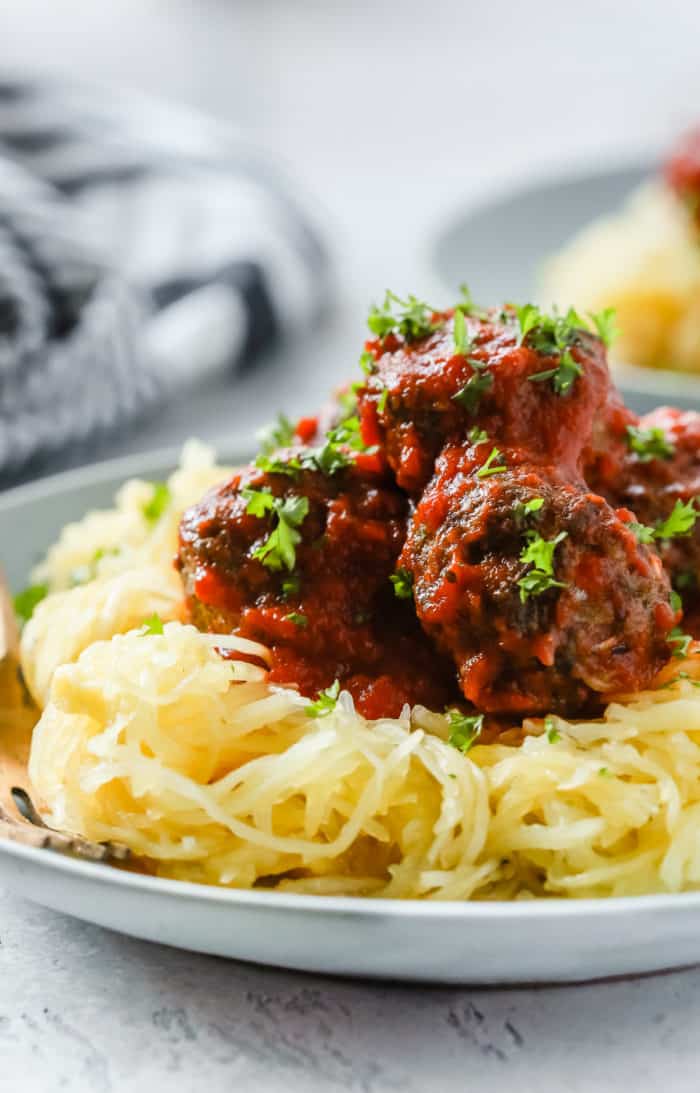 Close-up of half a spaghetti squash with meatballs on a white plate.