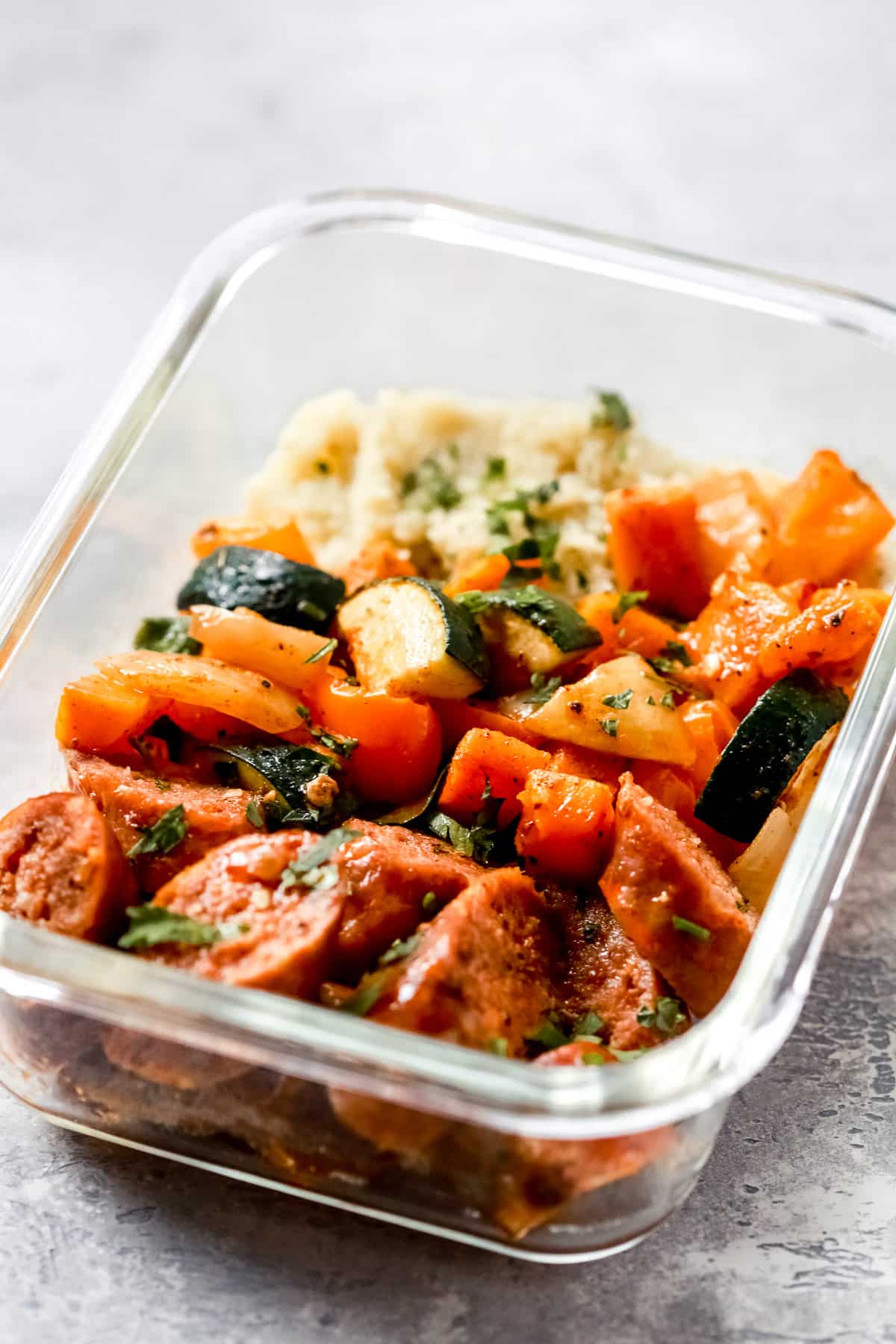 close up of a glass meal prep bowl of sausage and veggies