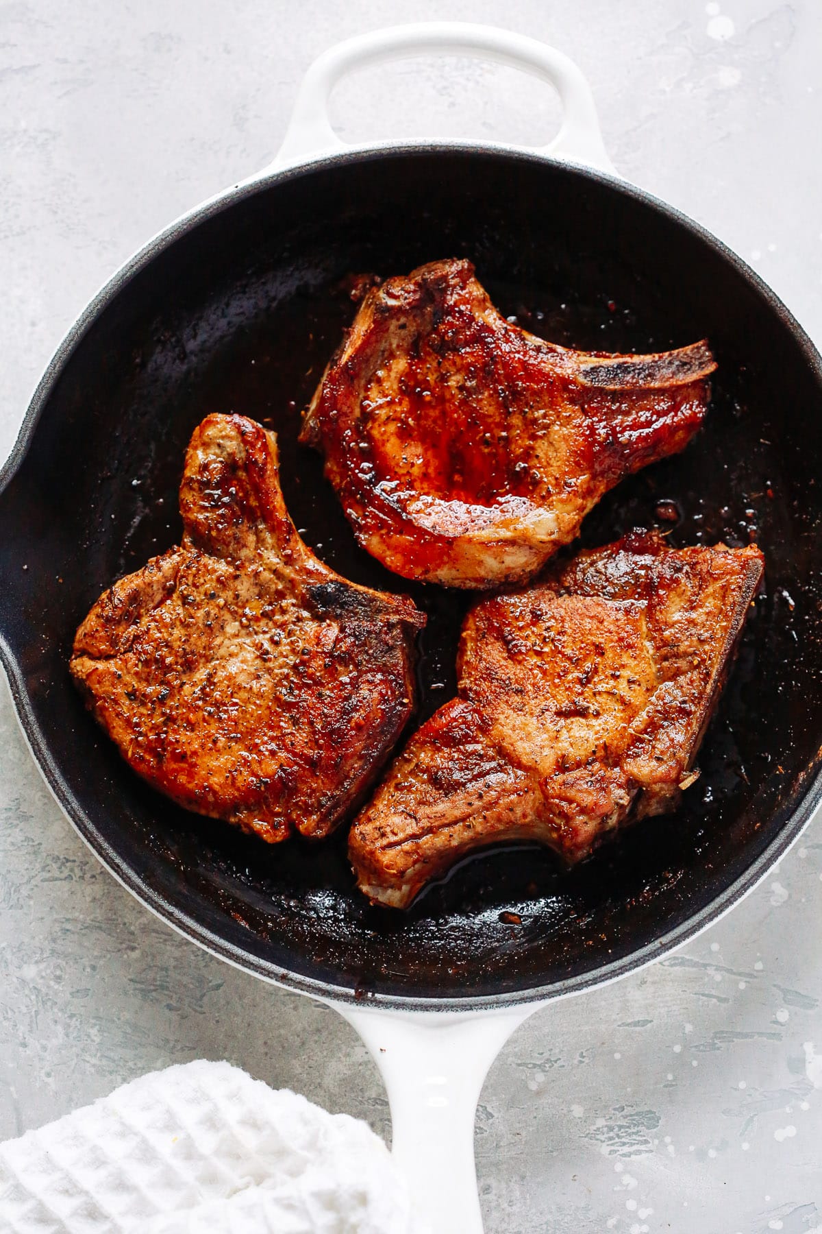 overhead view of a white skillet containing Pork chops