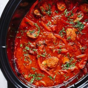 overhead view of a slow cooker pot containing Italian Sausage and bell pepper