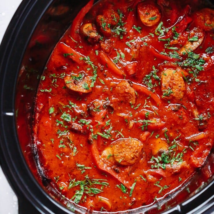 overhead view of a slow cooker pot containing Italian Sausage and bell pepper