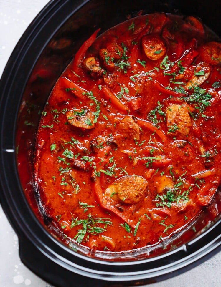 overhead view of a slow cooker pot containing Italian Sausage and bell pepper