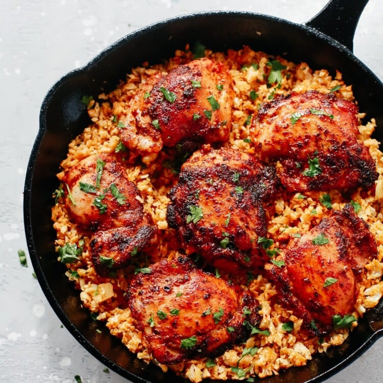 overhead view of black skillet with spicy chicken and cauliflower rice.