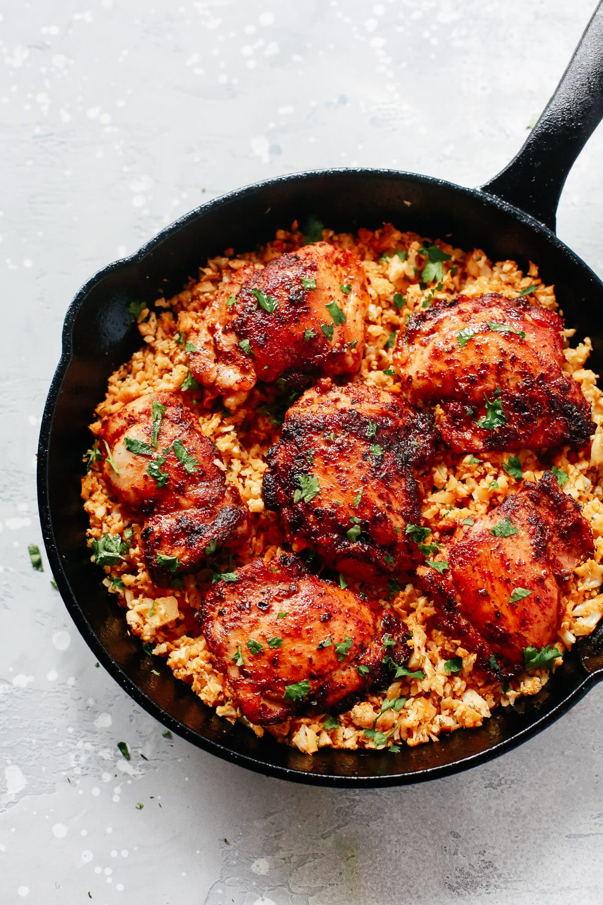 overhead view of black skillet with spicy chicken and cauliflower rice. 