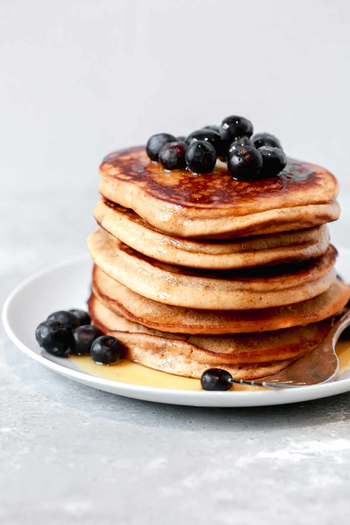 A stack of low carb almond flour pancakes with syrup and blueberries.