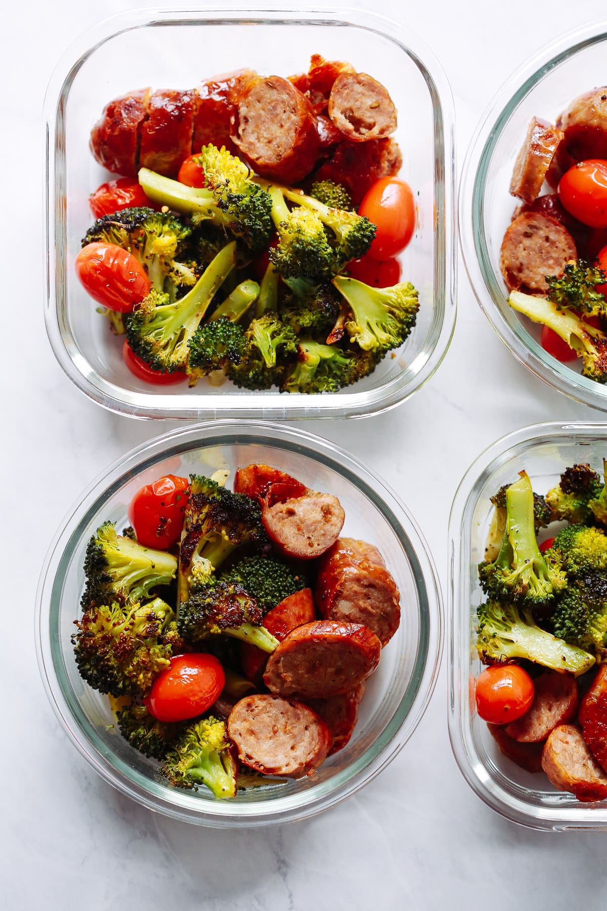 overhead view of 4 glass bowls containing Italian sausage and veggies. 