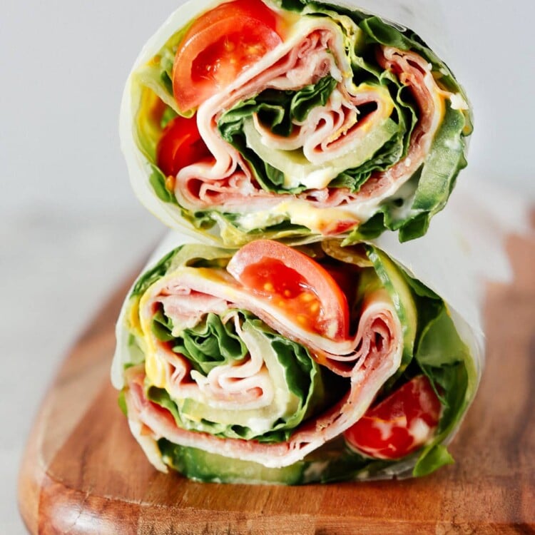 A lettuce wrap sandwich sitting on top of a wooden cutting board