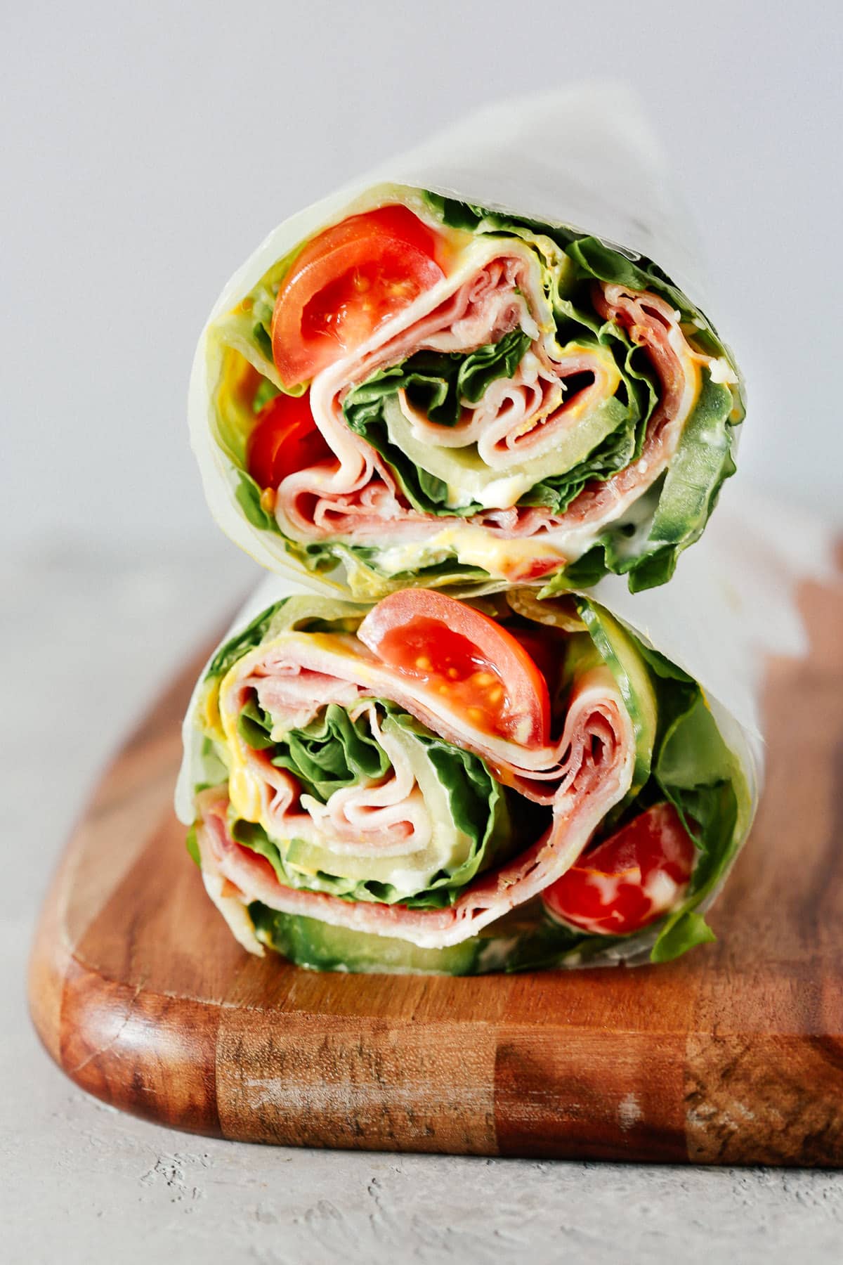 A lettuce wrap sandwich sitting on top of a wooden cutting board