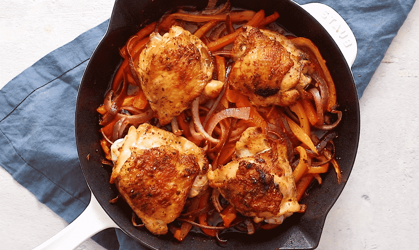 baked chicken with bell peppers and onions in a skillet