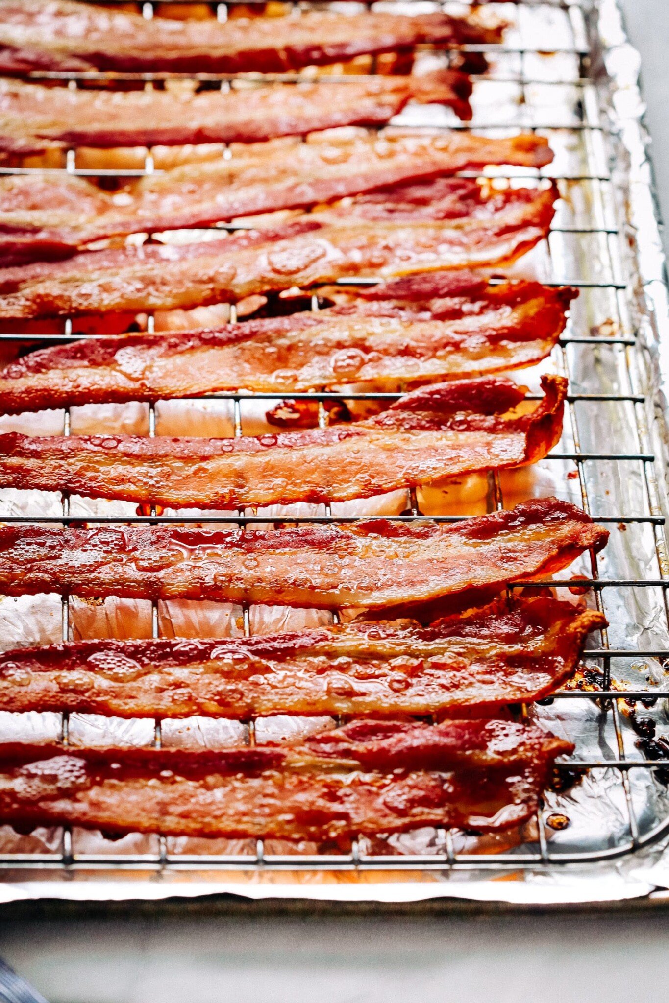 Cooked bacon on a wire rack atop a foil lined baking sheet.