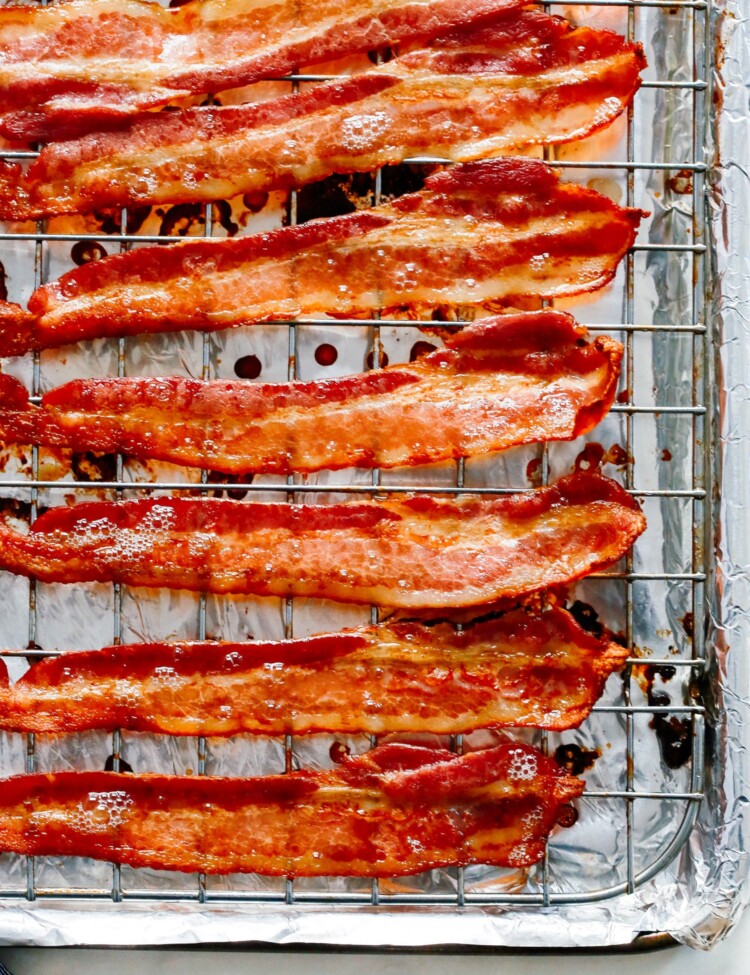 Cooked bacon on a wire rack atop a foil lined baking sheet.