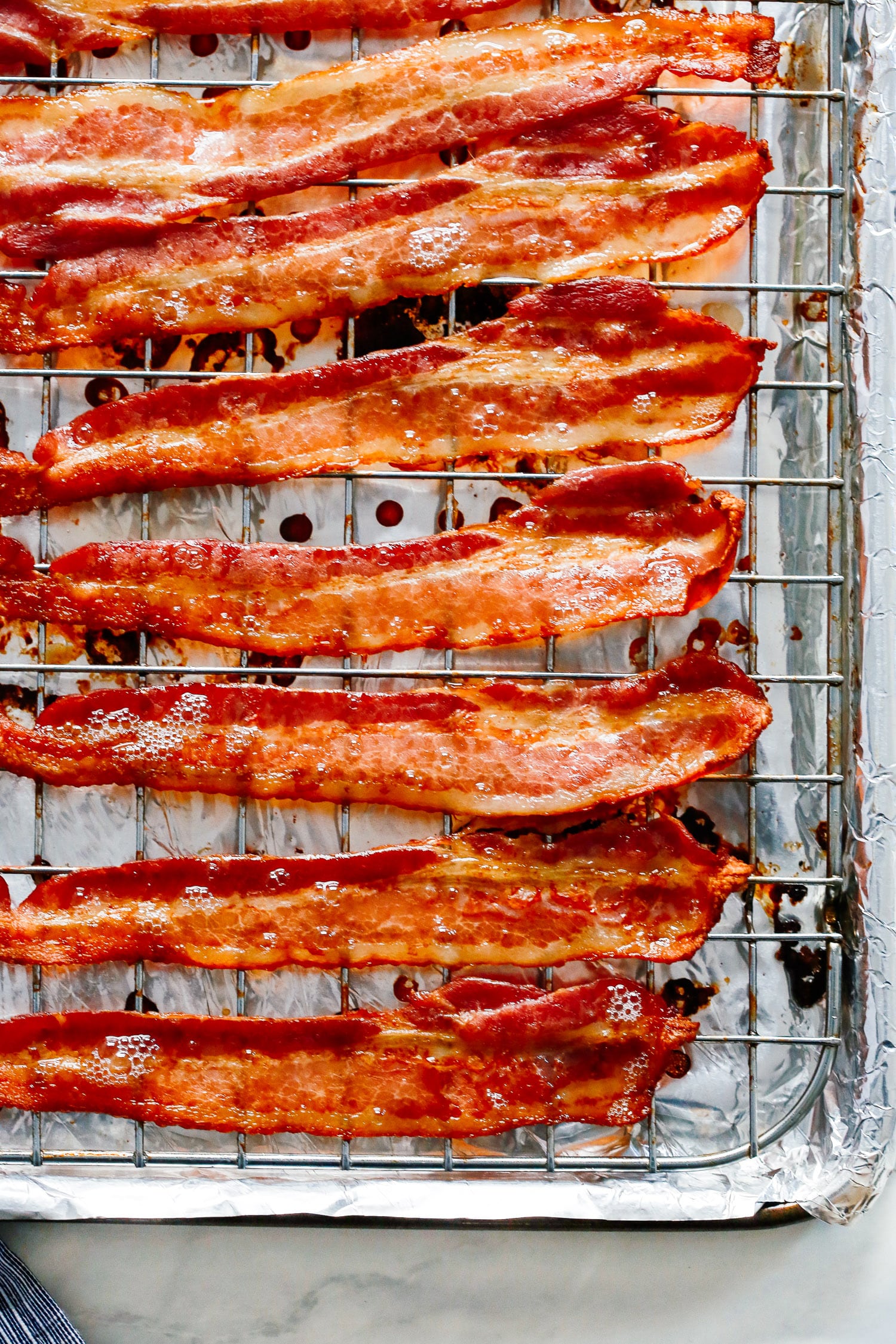 Cooked bacon on a wire rack atop a foil lined baking sheet.