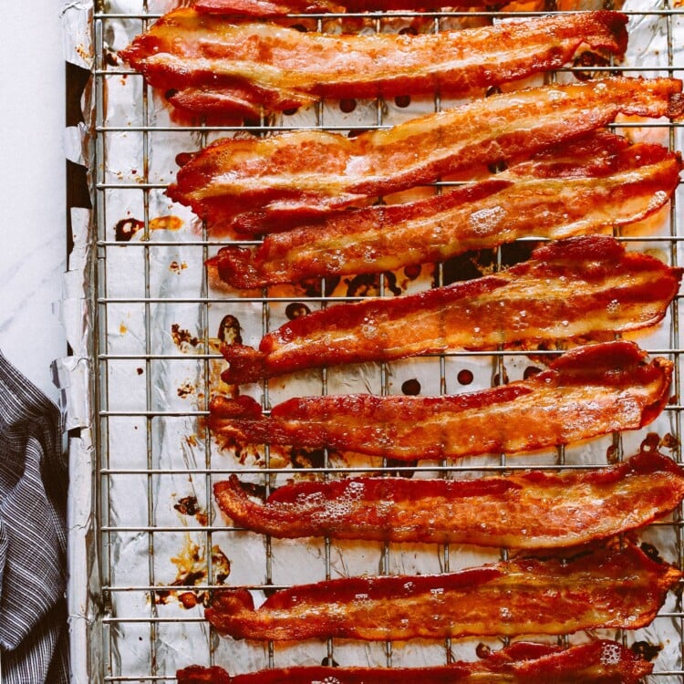 Cooked bacon on a wire rack atop a foil lined baking sheet.