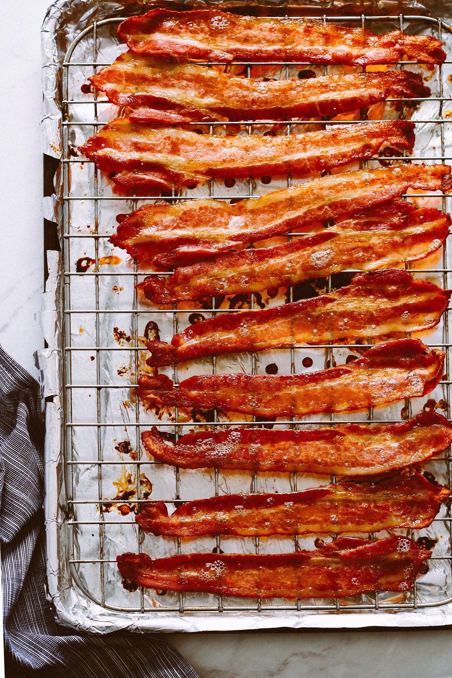 Cooked bacon on a wire rack atop a foil lined baking sheet.