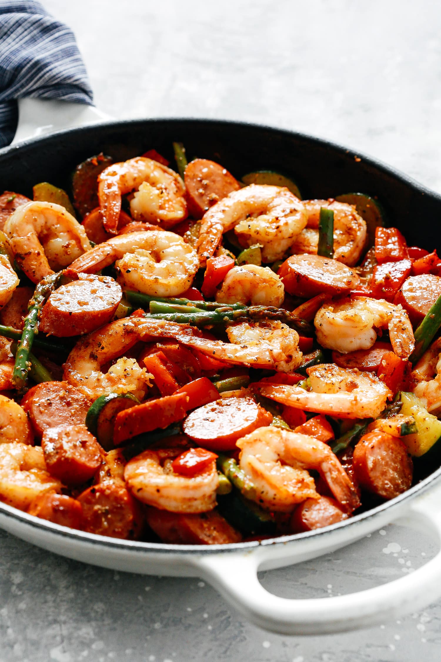 White skillet with shrimp and sausage inside.