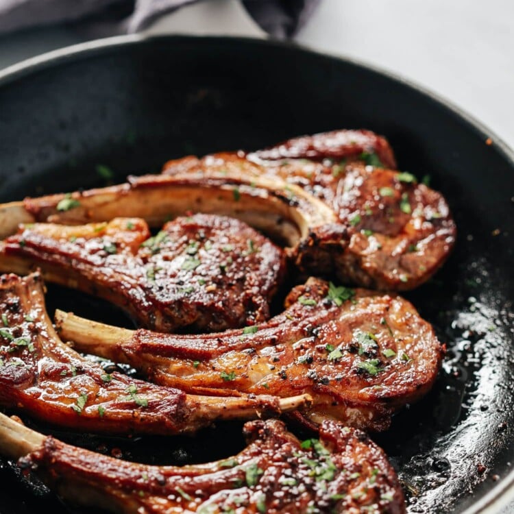 Overhead view of a skillet containing garlic butter lamb chops