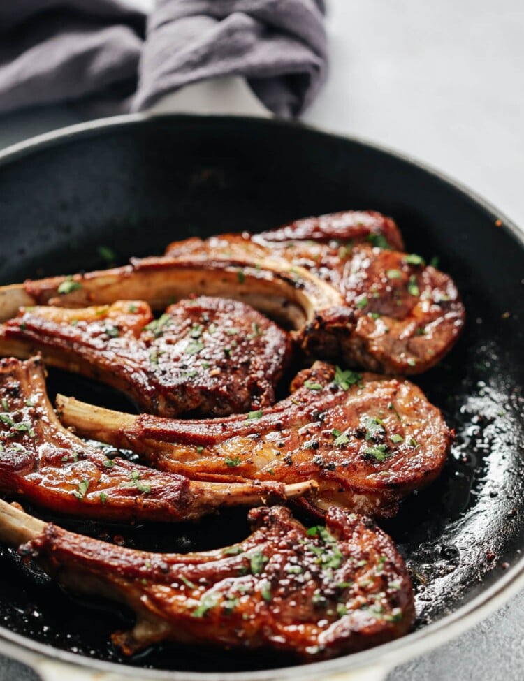 Overhead view of a skillet containing garlic butter lamb chops