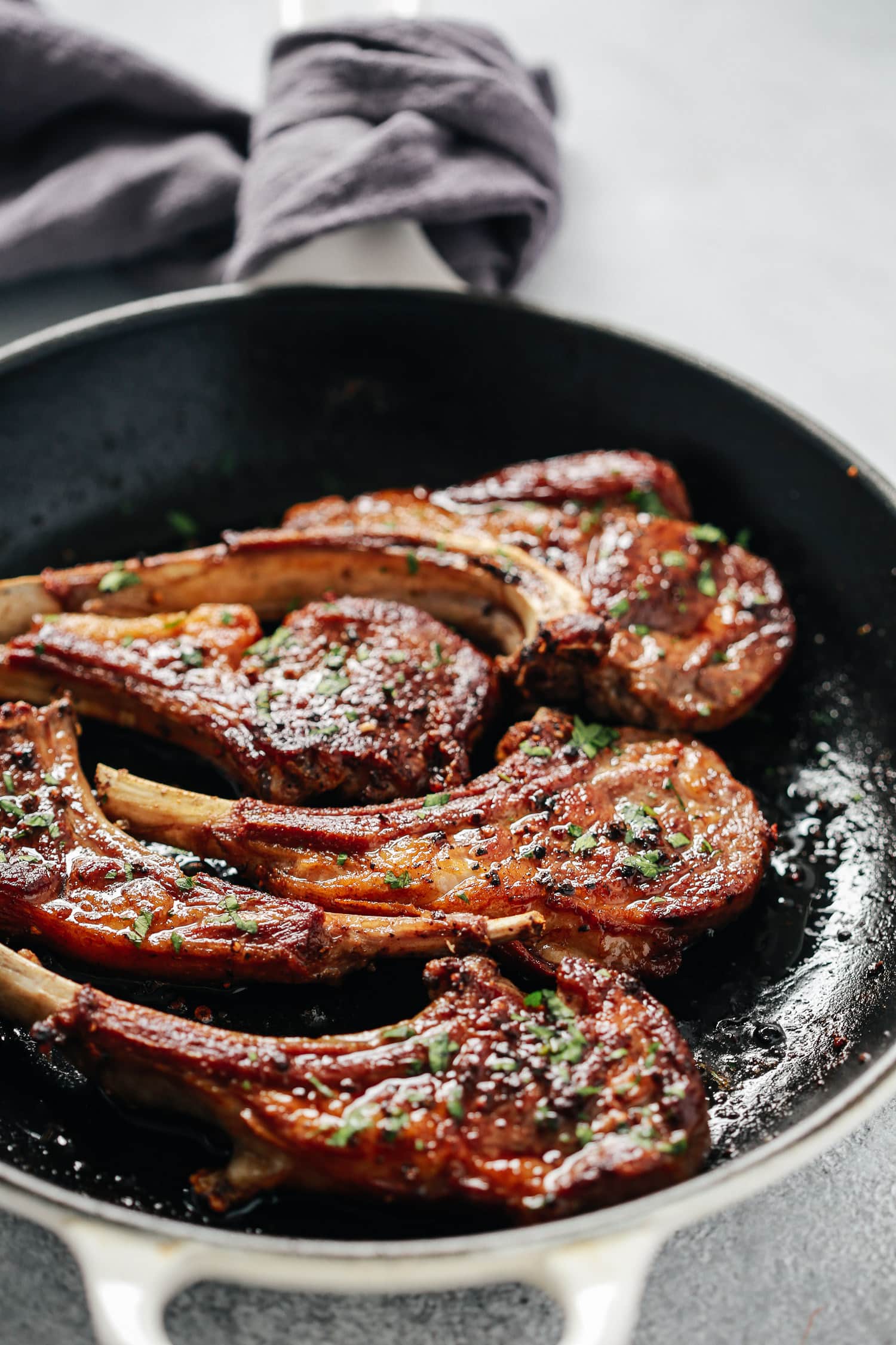 Overhead view of a skillet containing garlic butter lamb chop