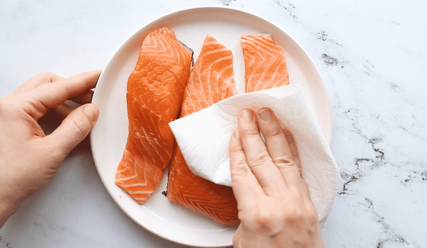 Patting the salmon fillets with a paper towel to dry