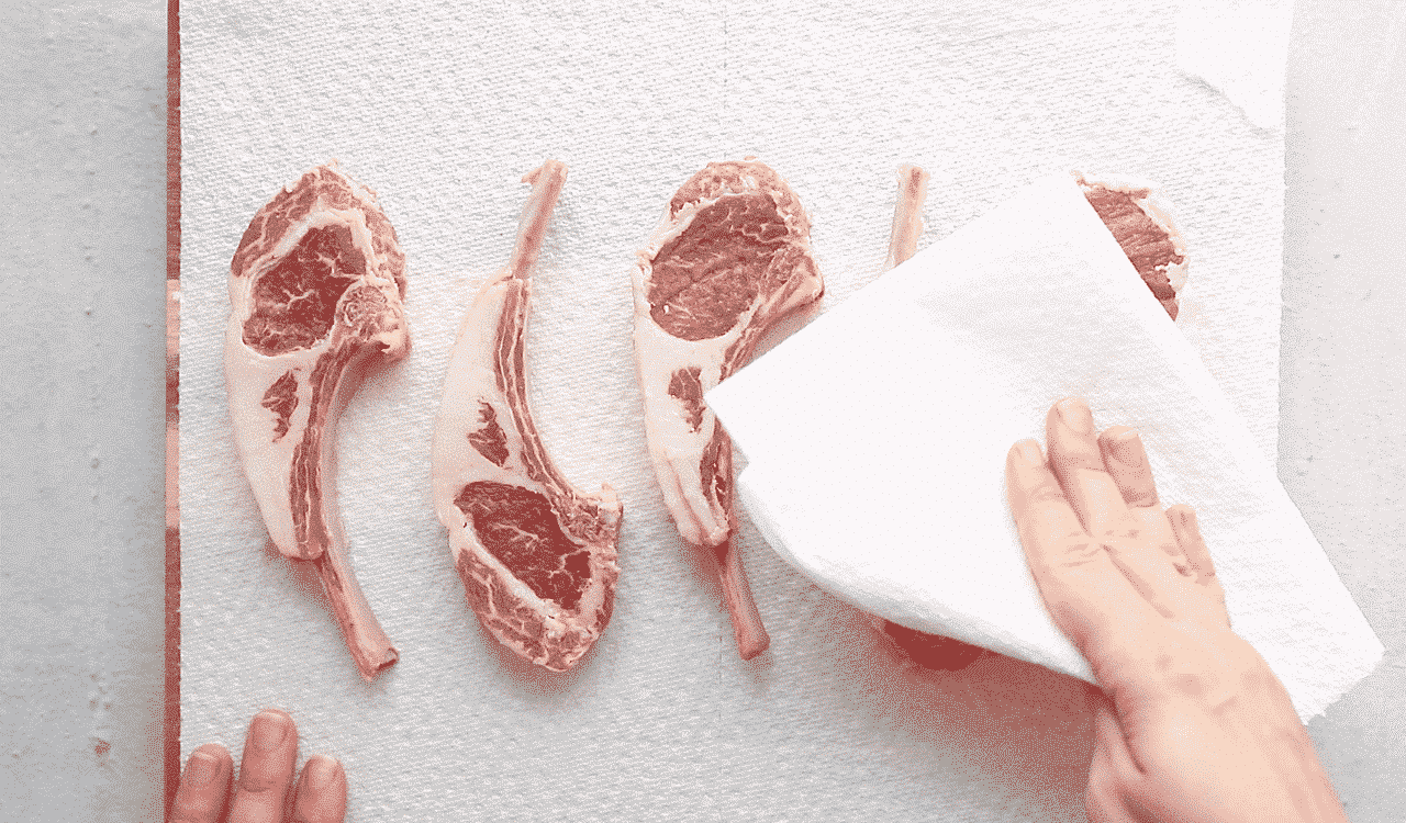 patting lamb chops dry with paper towels.