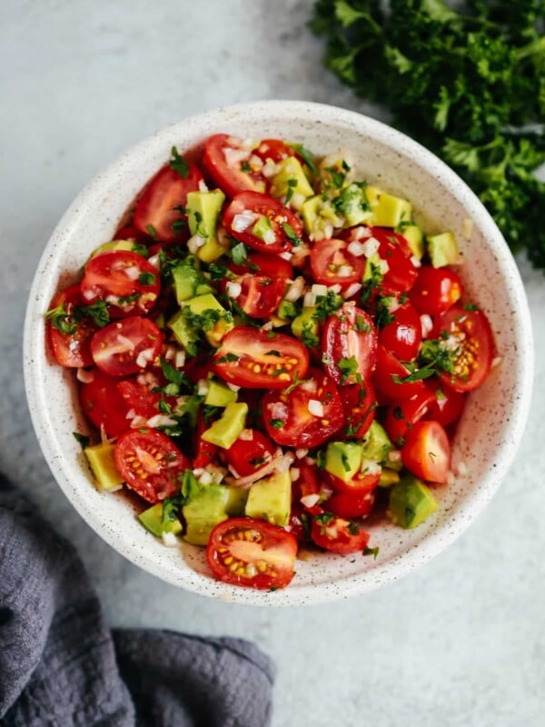 An overhead photo of an avocado tomato salad in a white bowl.